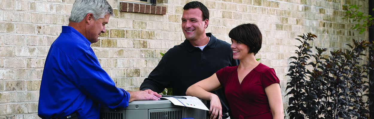 Hvac Tech And Homeowners Standing Next To An American Standard Heat Pump