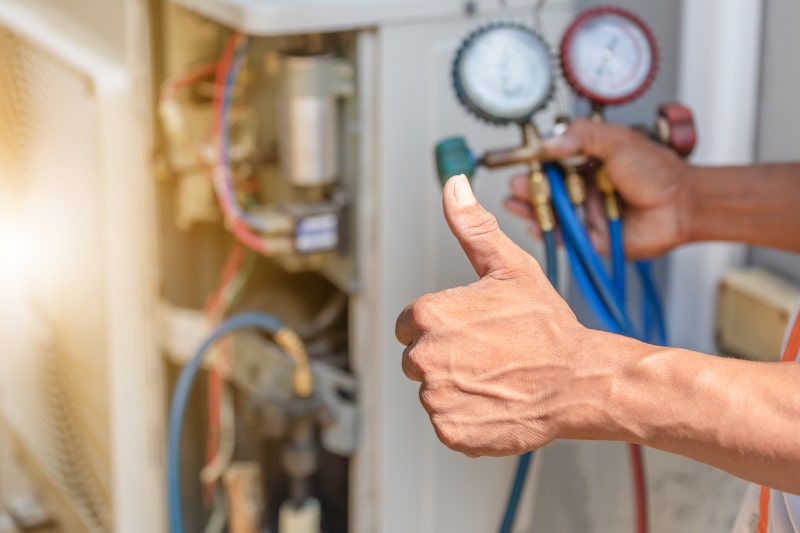 Technician giving thumbs up and checking gauges